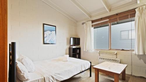 - une chambre avec un lit, une table et une fenêtre dans l'établissement Alpine Haven 7, à Mount Hotham