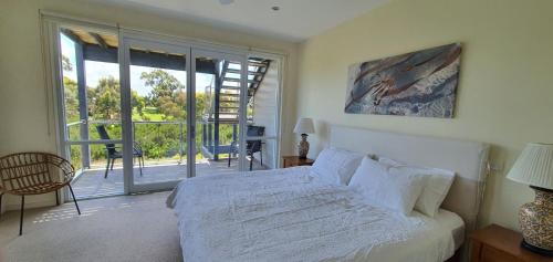 a bedroom with a white bed and a balcony at Coastal Soul Villa at Broadbeach in Inverloch