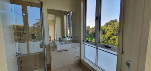 een badkamer met een douche, een wastafel en een raam bij Coastal Soul Villa at Broadbeach in Inverloch