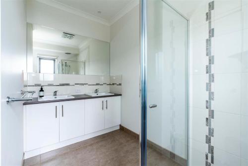 a white bathroom with a shower and a sink at Surfside Lakeviews Free Wifi in Inverloch