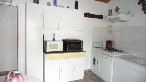 a small kitchen with white cabinets and a microwave at 15mn de Cannes, Villa la Soleiade , Gite ,Lodge , type T2, clim, piscine, parking au Lac de Saint-Cassien VAR in Montauroux