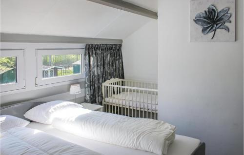 ブライニッセにあるStunning Home In Bruinisse With 3 Bedrooms And Wifiのベッドルーム1室(ベビーベッド1台、白いシーツ付きのベッド1台付)