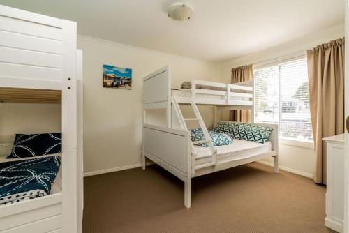 a bedroom with two bunk beds and a window at EAGLES NEST VIEWS ON TAMARA in Inverloch