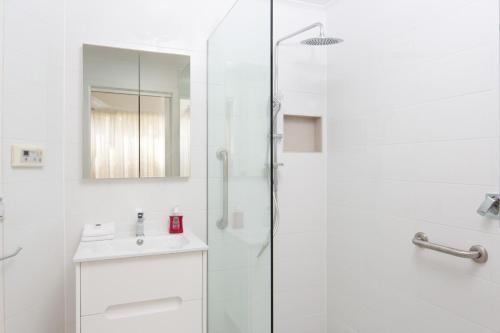 a white bathroom with a shower and a sink at Sails Two Inverloch in Inverloch