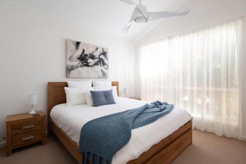 a bedroom with a bed with a blue blanket on it at Sails Two Inverloch in Inverloch