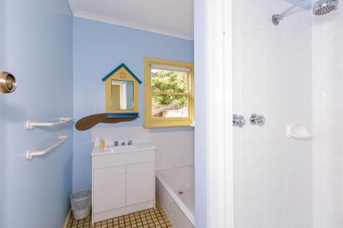 a bathroom with a shower and a sink and a tub at Holiday on Nautilus Inverloch in Inverloch