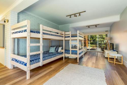 una camera con tre letti a castello in una casa di Hip Nautic 100 Metres to Beach a Inverloch