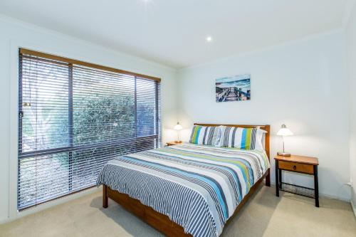 a bedroom with a bed and a large window at Surfside Getaway in Picturesque Inverloch in Inverloch