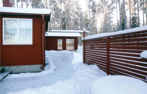 a cabin covered in snow next to a fence at Stunning Home In Vaggeryd With Sauna in Vaggeryd
