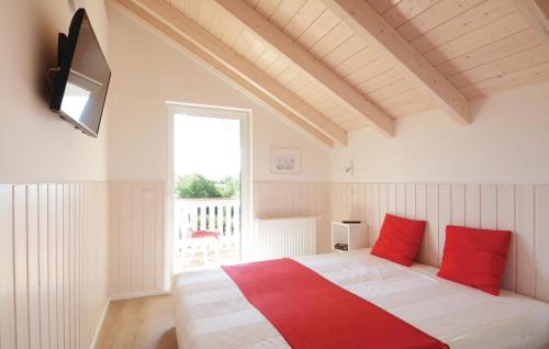 Un dormitorio con una cama con almohadas rojas y una ventana en Seeteufel 6, en Süssau