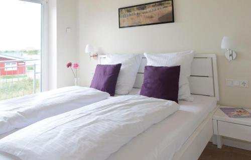 1 Schlafzimmer mit 2 weißen Betten und lila Kissen in der Unterkunft Ferienhaus Dageb�ll K�stenweg IV in Dagebüll