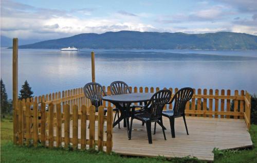 a table and four chairs on a wooden deck near the water at Lovely Home In Vågstranda in Hjelvik