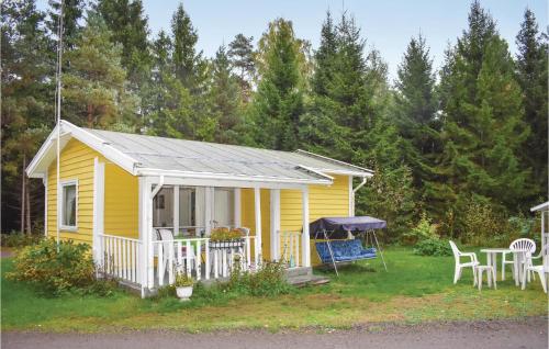 a yellow house with a table and chairs in the yard at One-Bedroom Holiday Home In Vittsjo in Vittsjö