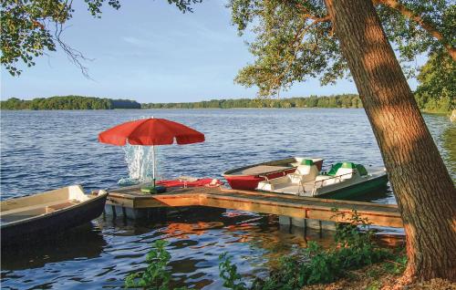 a dock with two boats and an umbrella on a lake at Cozy Home In Pinnow With Kitchenette in Petersberg