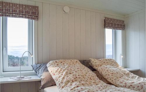 1 Schlafzimmer mit einem Bett mit Kissen und 2 Fenstern in der Unterkunft Cozy Home In Sndeled With House Sea View in Søndeled