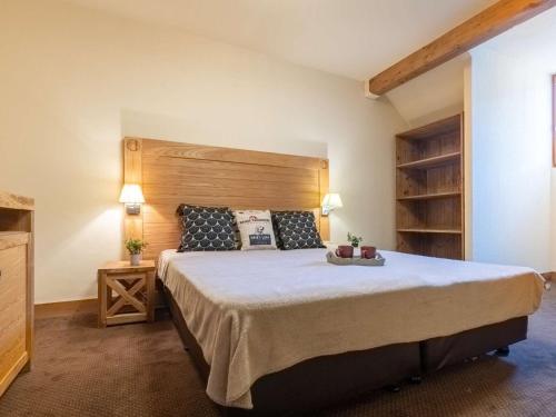 une chambre avec un grand lit avec une tête de lit en bois dans l'établissement Appartement Duplex Centre Saint-Lary avec Piscine, Sauna et Parking - FR-1-296-395, à Saint-Lary-Soulan