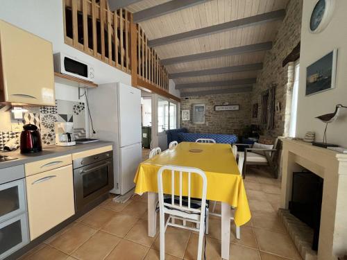 une cuisine avec une table et un chiffon de table jaune dans l'établissement Maison cosy au cœur du village, 4 couchages, proche plage et port, Wifi inclus - FR-1-246A-134, à Saint-Denis-dʼOléron