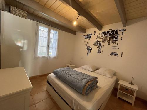 - une chambre avec un lit à baldaquin sur le mur dans l'établissement Maison cosy au cœur du village, 4 couchages, proche plage et port, Wifi inclus - FR-1-246A-134, à Saint-Denis-dʼOléron