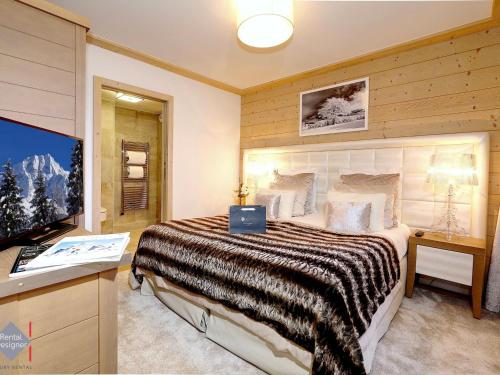 Appartement Courchevel 1550, 3 pièces, 4 personnes - FR-1-664-5 في كورشوفيل: غرفة نوم بسرير كبير وتلفزيون