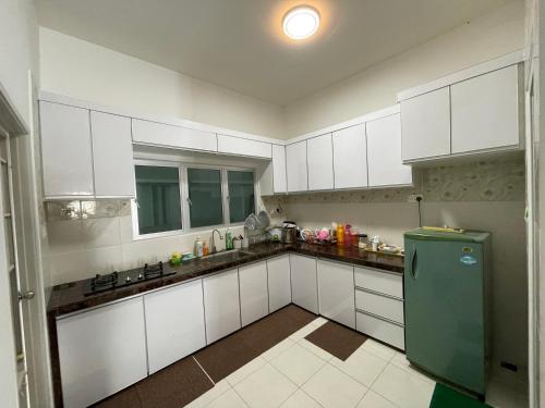 バヤンレパスにあるNORISH HOMESTAYのキッチン(白いキャビネット、緑の冷蔵庫付)