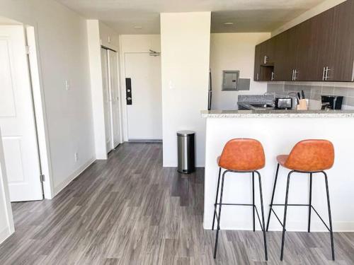 a kitchen with two orange chairs at a counter at Sleepover Downtown Cincinnati 1BD 1BA Apartments in Cincinnati