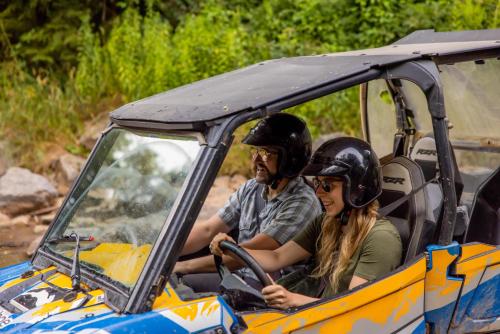 a man and woman wearing helmets sitting in an atv at Allegheny Spring 239 KING, bed/Ski-In, Out/Pool & Hot Tub in Snowshoe