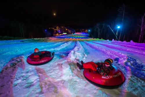 two people are riding down a snow covered road in tubes at Allegheny Spring 239 KING, bed/Ski-In, Out/Pool & Hot Tub in Snowshoe