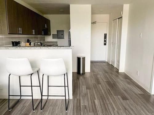 a kitchen with two white stools and a counter at Sleepover Downtown Cincinnati 1BD 1BA Apartments in Cincinnati