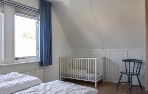 een slaapkamer met een wieg, een stoel en een raam bij 3 Bedroom Awesome Home In Zonnemaire in Zonnemaire