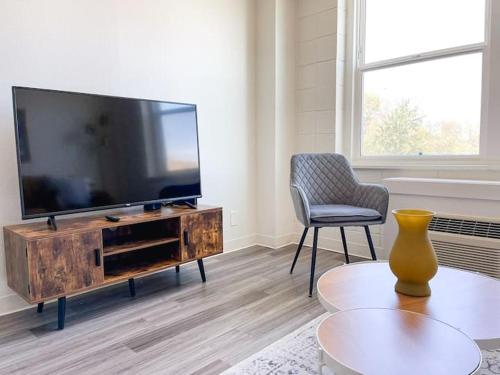 a living room with a flat screen tv and a chair at Sleepover Downtown Cincinnati 1BD 1BA Apartments in Cincinnati