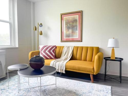 a living room with a yellow couch and a table at Sleepover Downtown Cincinnati 1BD 1BA Apartments in Cincinnati