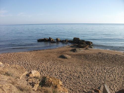 a sandy beach with rocks in the water at Apartment Timpirussimare in Sciacca