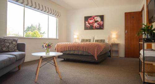 Ranfurly Motels في Ranfurly: غرفة نوم بسرير واريكة وطاولة