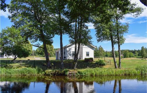 a white house with trees next to a pond at Cozy Apartment In Lagan With Wifi in Lagan