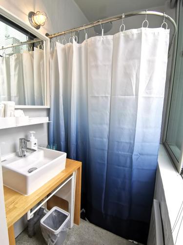 a bathroom with a blue shower curtain and a sink at SHhotel 1フロア貸切り 広々2LDK in Naha