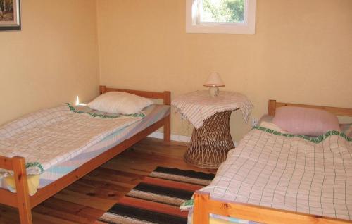 NyhamnにあるStunning Home In Visby With Kitchenのベッド2台、テーブル(ランプ付)が備わる客室です。