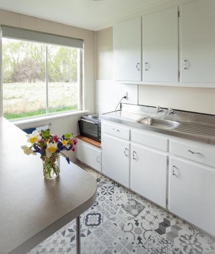a kitchen with white cabinets and a vase of flowers on a table at Ranfurly Motels in Ranfurly