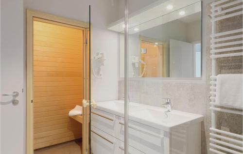 La salle de bains blanche est pourvue d'un lavabo et d'un miroir. dans l'établissement Dnenvilla Deluxe, à Priwall