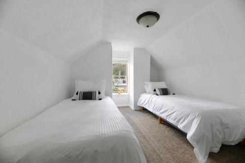 een witte kamer met 2 bedden en een raam bij The Overlook Nook in Lead