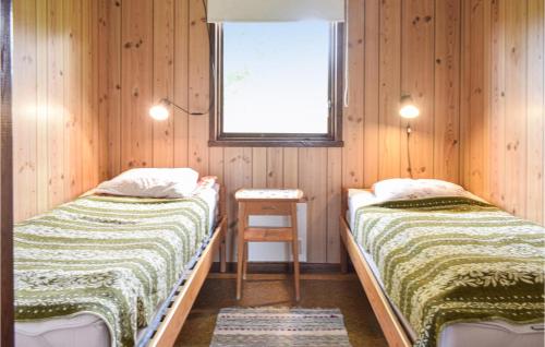 シーピンスリーにあるBeautiful Home In Kpingsvik With 2 Bedroomsのウッドウォールと窓が備わるドミトリールームのベッド2台分です。
