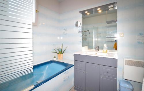 Amazing Home In Borgo With Kitchen في بورجو: حمام مع حوض استحمام أزرق ومغسلة
