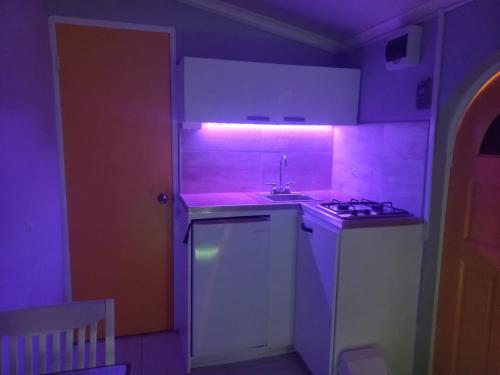 - une cuisine avec un évier et une lumière violette dans l'établissement The Brayan's Apartment, à Oranjestad