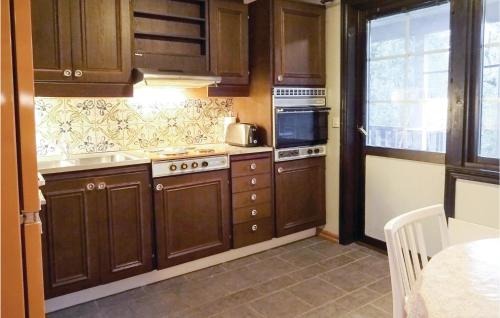 a kitchen with wooden cabinets and a stove top oven at Four-Bedroom Holiday Home In Hasslo in Sissehall