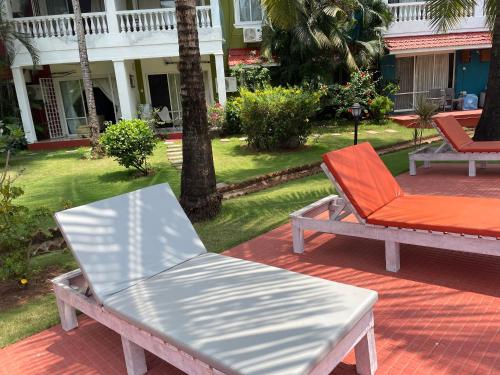 a bench and an orange chair on a patio at Sun-kissed Holidays Goa-Sapphire in Siolim