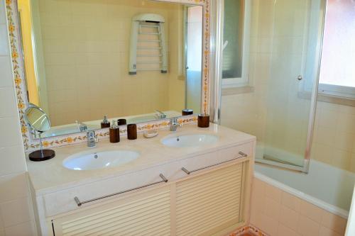 uma casa de banho com 2 lavatórios e um chuveiro em Apartamento Golf Resort em Charneca de Caparica