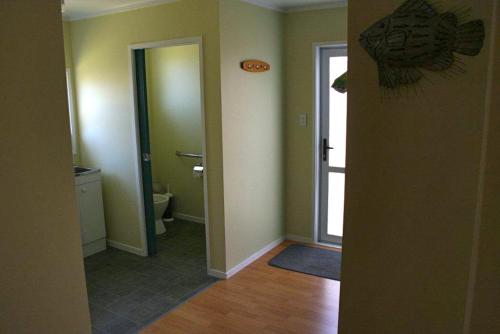 - un couloir avec une salle de bains pourvue de toilettes et d'une porte dans l'établissement Matapouri Cottage - Matapouri Holiday Home, à Matapouri