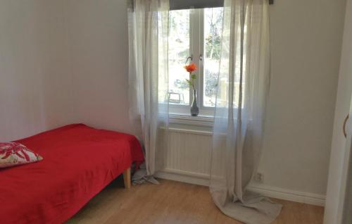 Un dormitorio con una cama roja y una ventana con una flor en Gorgeous Home In Flen With Sauna en Flen