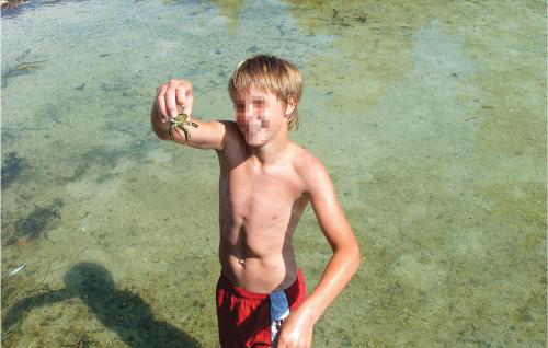 a young boy is standing in the water at Beautiful Home In Hatlestrand in Hatlestrand
