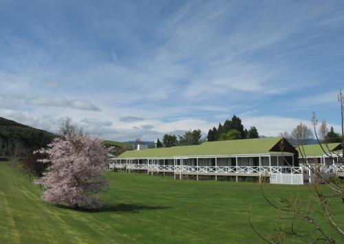 a large building with a green roof and a tree at Turangi Bridge Motel in Turangi