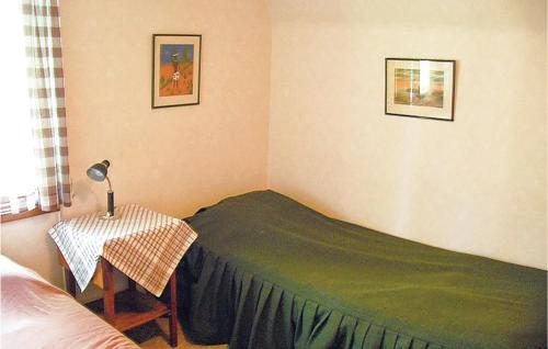 2 Bedroom Awesome Home In Mrbylnga في Stora Frö: غرفة نوم بسرير اخضر وطاولة